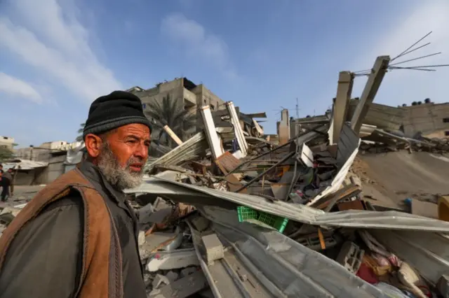 A Palestinian man looks on at the destruction
