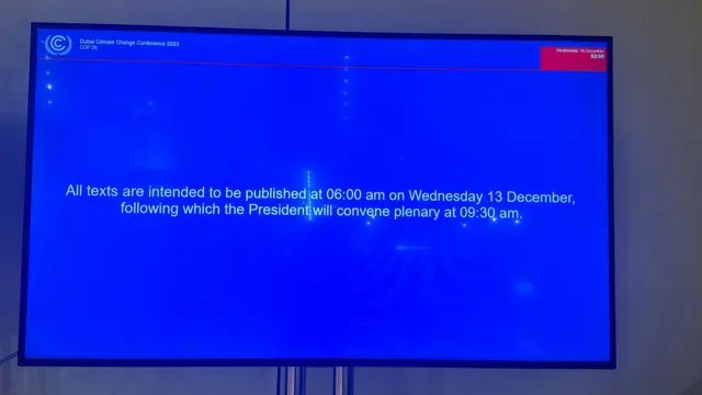 TV screen with blue background and message that reads: "All texts are intended to be published at 06:00am on Wednesday 13 December following which the President will convene plenary at 9:30am."