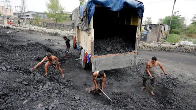 Labourers load coal onto a supply truck on the outskirts of Jammu, April 6, 2017.