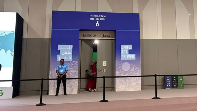 A woman walks into meeting room six at COP26