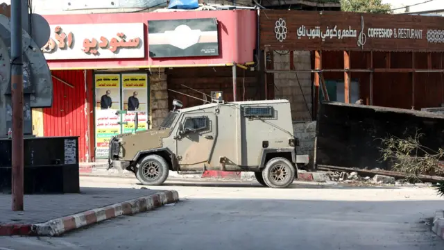 An Israeli military vehicle is stationed on a street at the Jenin refugee camp during a raid by the Israeli forces