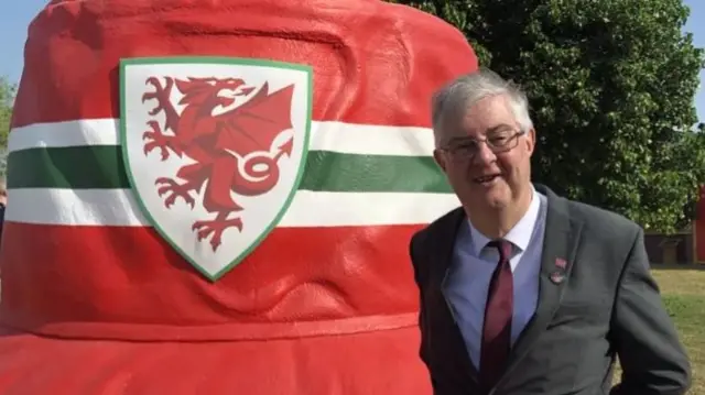 Mark Drakeford in front of giant bucket hat