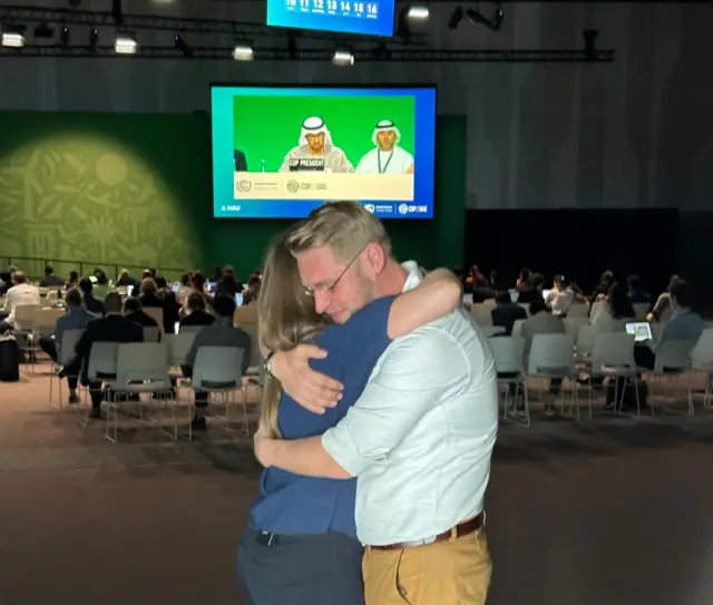 Two observers hug in the overflow room at COP28