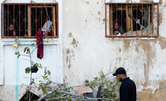 Palestinian women look out of a house damaged in an Israeli strike, amid the ongoing conflict between Israel and the Palestinian Islamist group Hamas