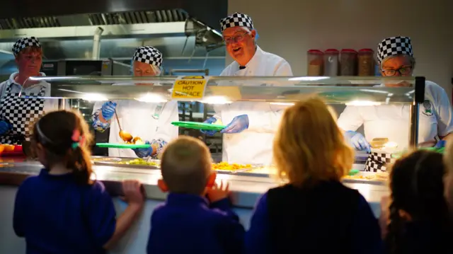 Mark Drakeford serving meals to children at a school