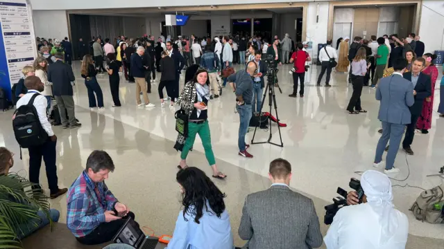 Dozens of reporters and delegates standing and sitting at COP28