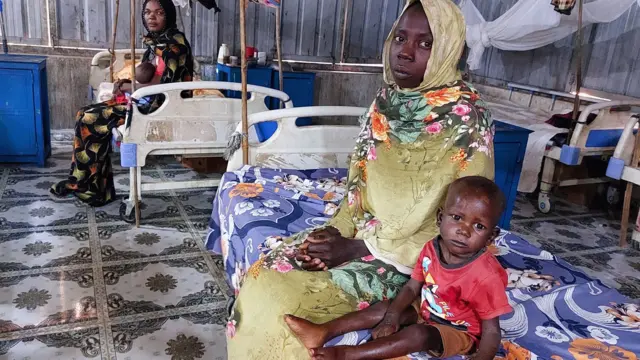 Women and a children sit waiting at a nutrition centre at the Kalma camp for the displaced just outside Nyala, the provincial capital of South Darfur state