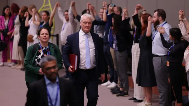 Graham Stuart, UK climate minister, walks through protestors at COP28