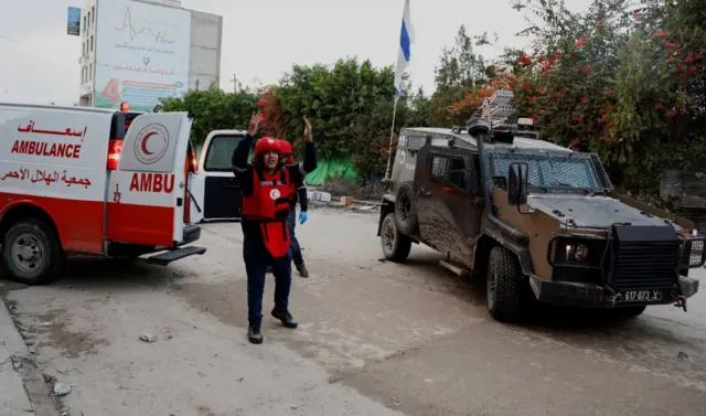 A medic reacts as an Israeli military vehicle blocks an ambulance carrying an injured person during an Israeli military raid in Jenin