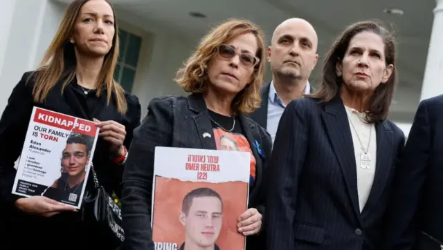 Relatives of US hostages hold up photos of their loved ones after a meeting with President Joe Biden on 13 December 2023