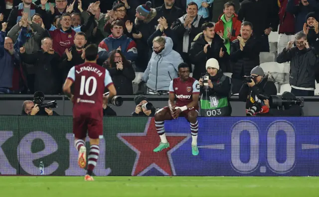 Mohammed Kudus of West Ham United celebrates by sitting on the advertisement hoardings