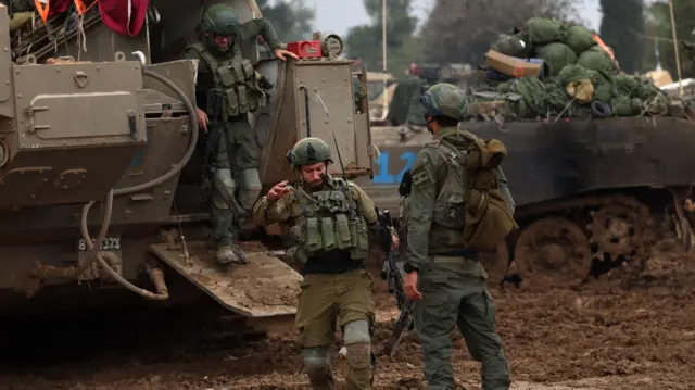 Israeli soldiers step out of an armoured vehicle at an undisclosed location near the Gaza border