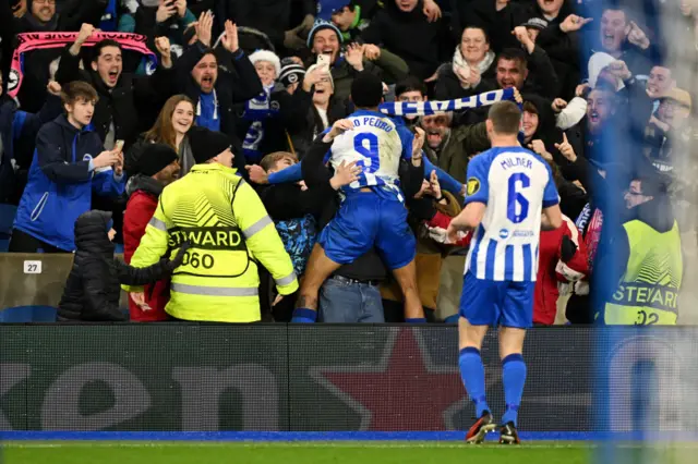 Brighton & Hove Albion's Joao Pedro celebrates by jumping into the stands