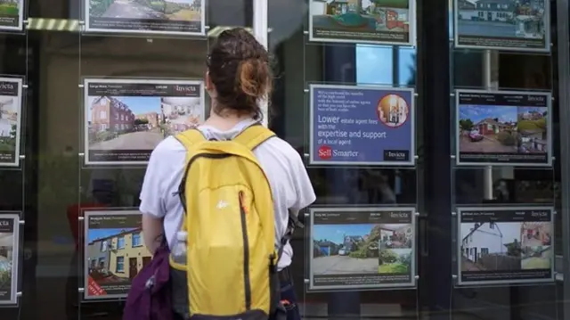 woman looking at estate agent's window