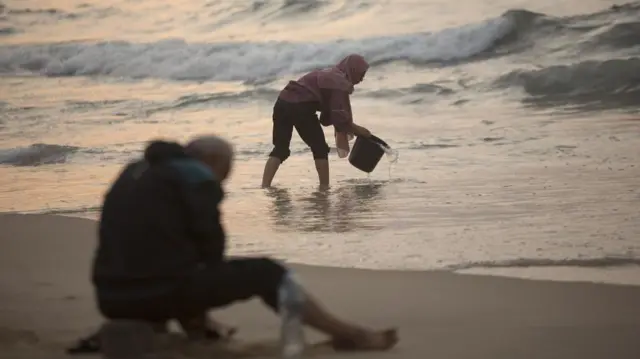 A Palestinian woman washes clothes with sea water at Deir al-Balah beach