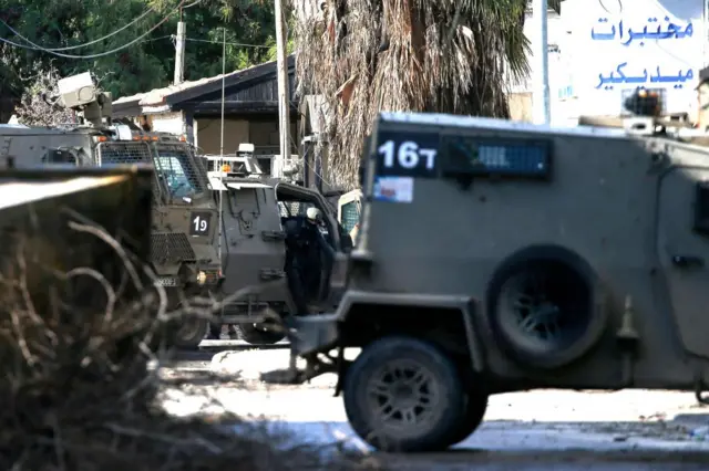 A soldier is seen in an Israeli military vehicle stationed on a street as the Israeli forces' raid on Jenin refugee camp continues for a third consecutive day