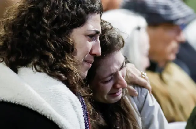 A woman comforts the wife of Israeli military commander Lieutenant Colonel Tomer Grinberg, who was killed in northern Gaza amid the Israeli army's ongoing ground operation in the Gaza Strip, as she mourns during Grinberg's funeral at Mount Herzl military cemetery in Jerusalem, December 13, 2023.