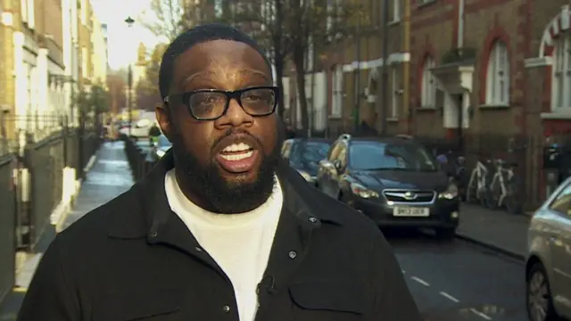 Emmanuel Asuquo speaking to a camera on a sunny street