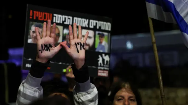 A woman raises her hands with the words "No time" written on them as she attends a rally calling for the release of hostages in Jerusalem