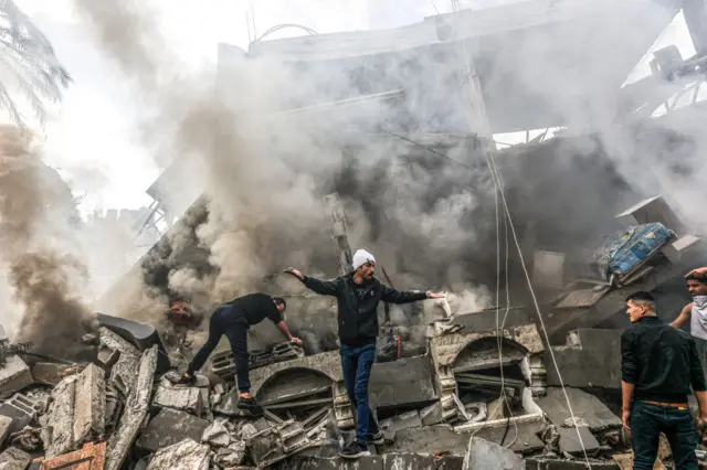 Palestinians climb through the wreckage of a building in the southern Gaza Strip