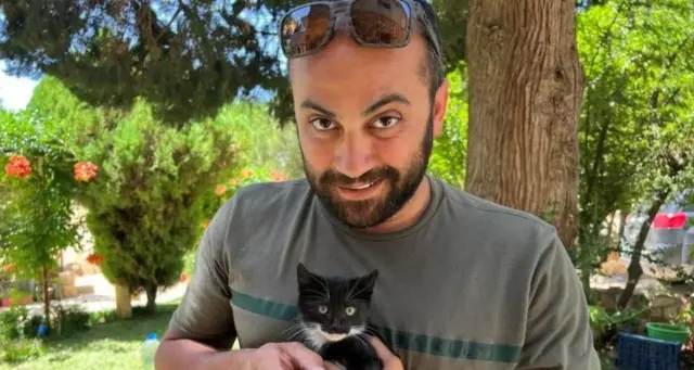 Reuters visuals journalist Issam Abdallah holds a kitten while posing for a picture in Saaideh, Lebanon