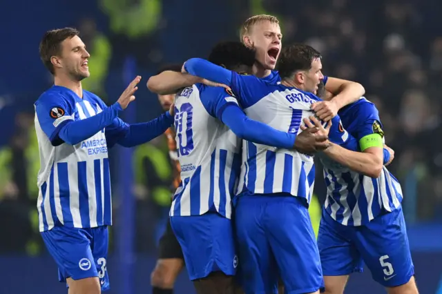 Brighton players celebrate as a group in a huddle