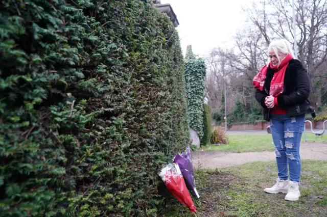 A woman laying flowers outside Wensum Park in Norwich,