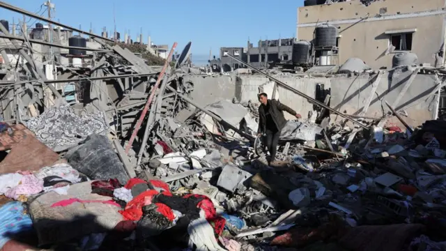 A Palestinian man walks on ruins at the site of an Israeli strike on a house in Rafah