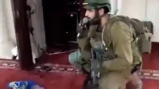 Still frame of Israeli soldier using a microphone to recite a prayer in a mosque in Jenin