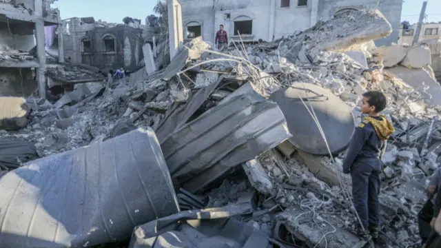 A small boy stands on a pile of rubble in Rafah