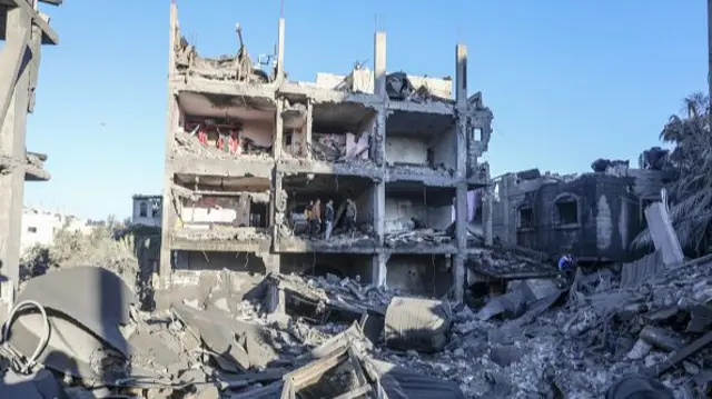 Civil defense teams and Palestinians conduct search and rescue operations among the rubble of buildings in Rafah, 15 December 2023