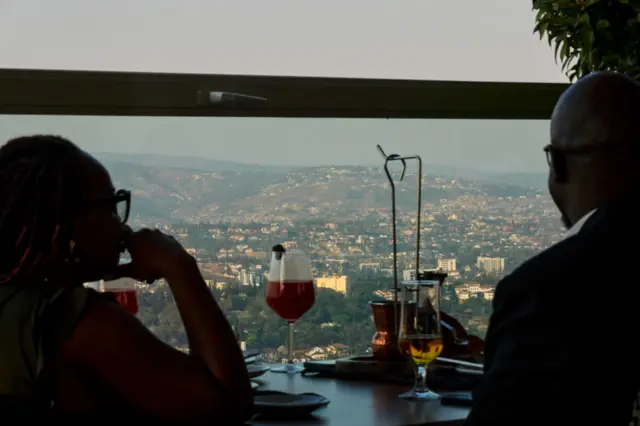 Diners look out towards the Kigali skyline from the rooftop restaurant of the Ubumwe Grande Hotel in the Nyarugenge district of Kigali, Rwanda on Thursday, July 20, 2023.