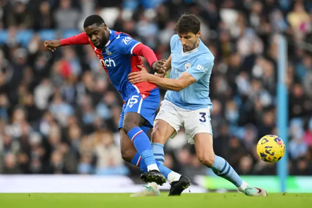 Jeffrey Schlupp of Crystal Palace is challenged by Ruben Dias of Manchester City