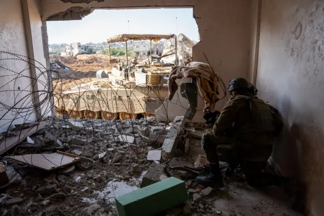 Israeli soldier setting up in rubble of building in Gaza