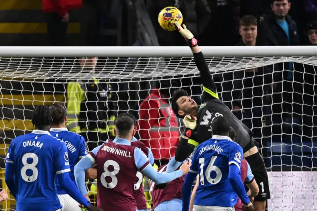 Trafford gets fingertips to save a cross diverting into the net.