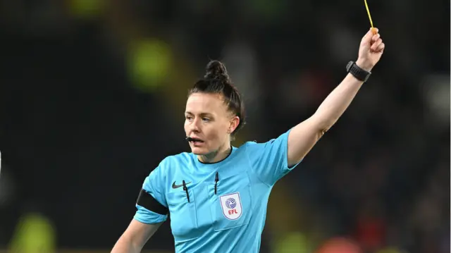 Referee Rebecca Welch shows a yellow card