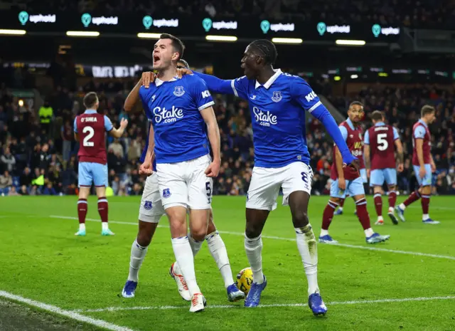 Michael Keane roars at the away fans to celebrate his goal, alongside teammates.