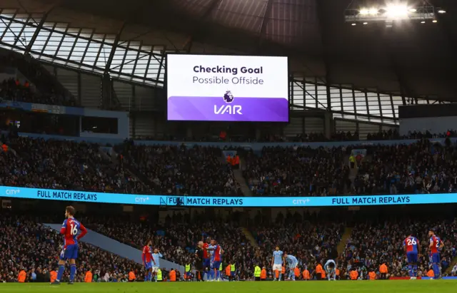 The big screen displays a VAR review message after Manchester City's Jack Grealish scores their first goal