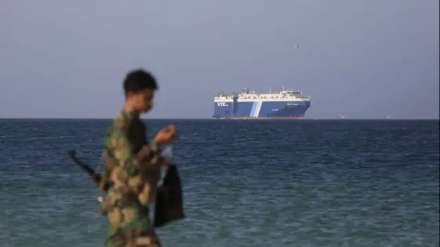 Soldier walking past port with ship in distance