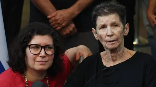 Yocheved Lifschitz speaks with the media next to her daughter Sharone