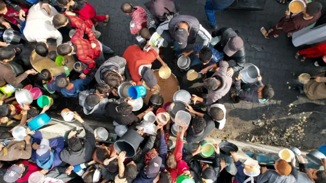 An aerial shot of people crowding around a food pot