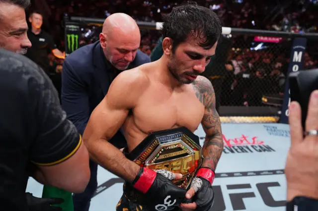 Dana White places the championship belt around Alexandre Pantoja