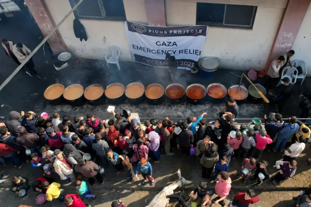 People gathering in front of pots of hot food