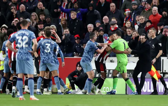 Emiliano Martinez and John McGinn of Aston Villa clash with Mathias Zanka Jorgensen of Brentford