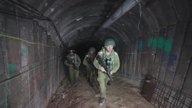 Army officers walking with weapons through the tunnel