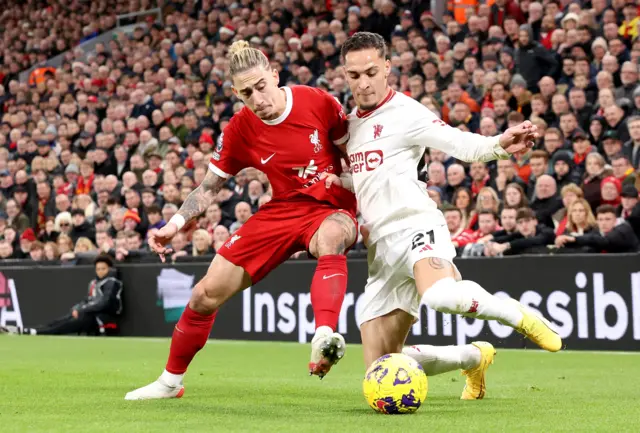 Kostas Tsimikas (L) of Liverpool in action against Antony of Manchester United