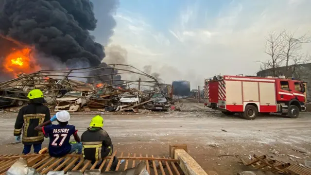 Firemen monitor the fire after a blast at an oil terminal in Conakry, Guinea December 18, 2023