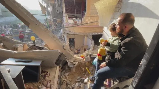 Jihad Zoorob and his daughter sitting amid the rubble in Rafah