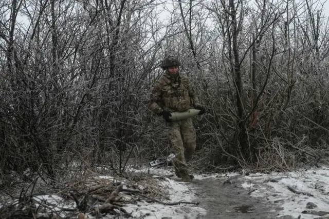 A Ukrainian soldier carries a shell for a self-propelled howitzer at a position in a front line near the town of Bakhmut