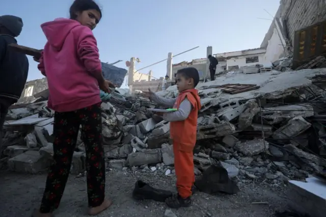 Palestinian children by the rubble of a destroyed house following an Israeli air strike in the east of Deir al Balah